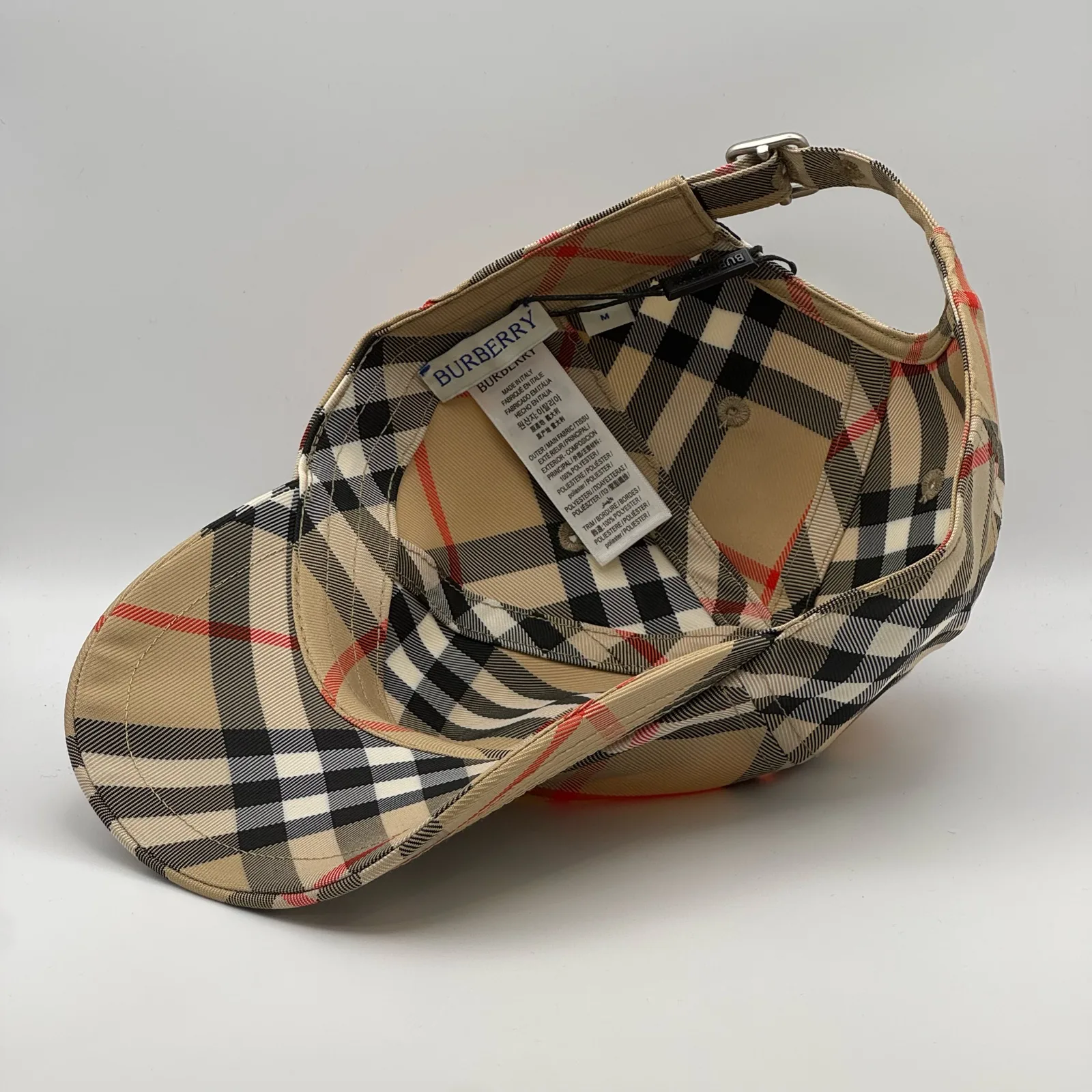 Underside of the beige check cap, brim lifted to show the interior and tag.