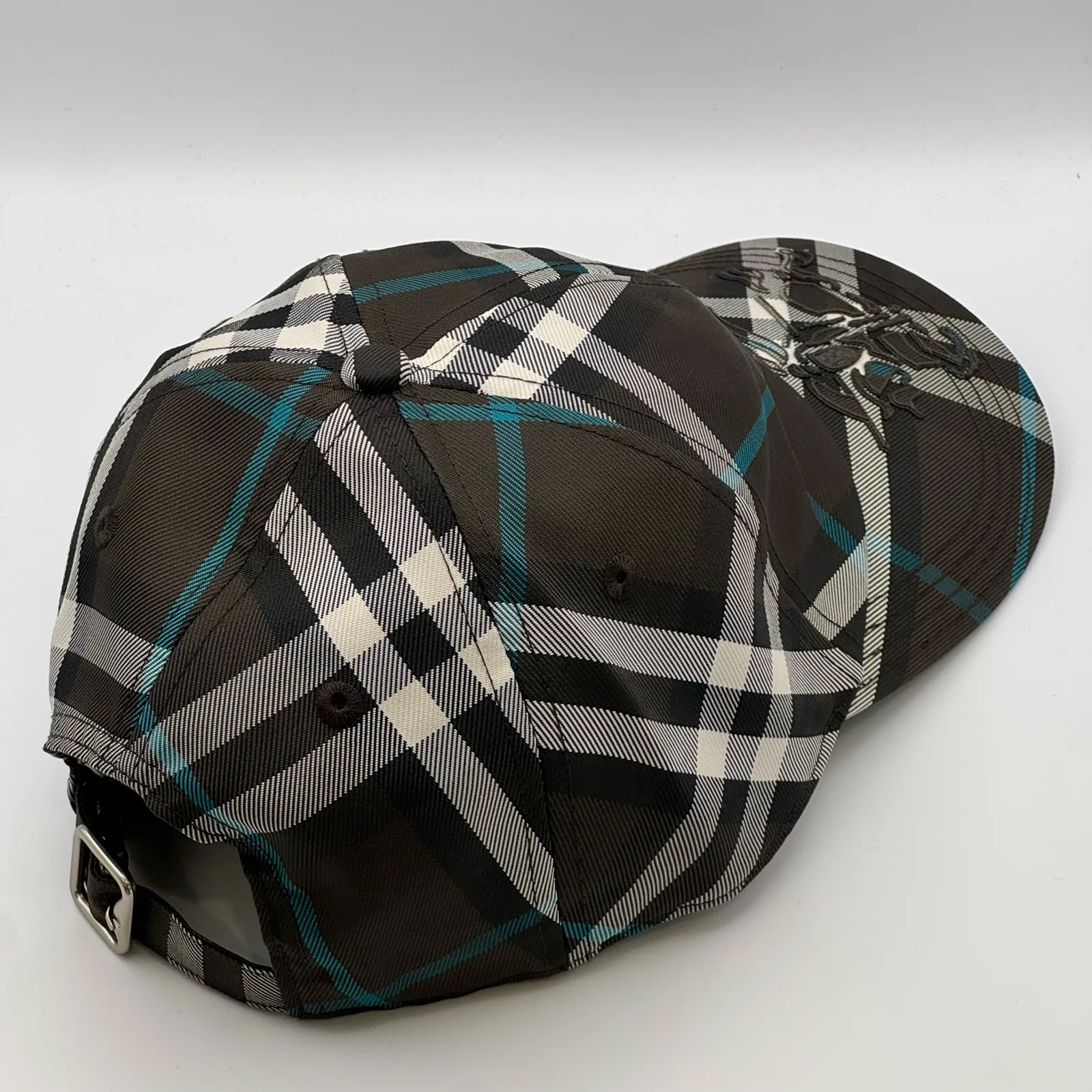 Dark brown check Burberry cap, elevated three-quarter view of the crown.
