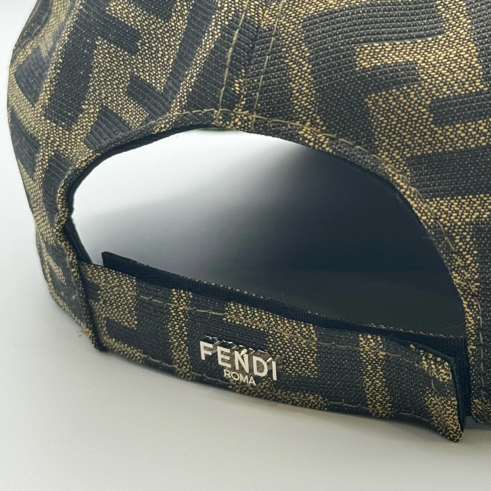Close-up of the Fendi Roma tab on the back strap of the brown FF cap.