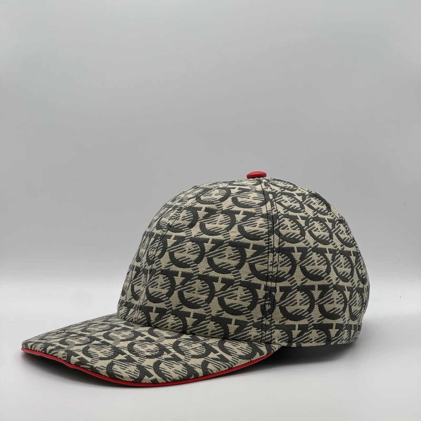 Ferragamo Gancini cap, side profile in the woven Gancini print with red trim.