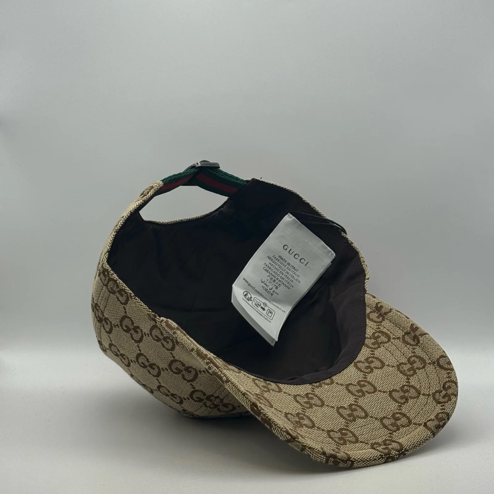 Beige GG canvas cap, brim lifted showing the interior lining and brand tag