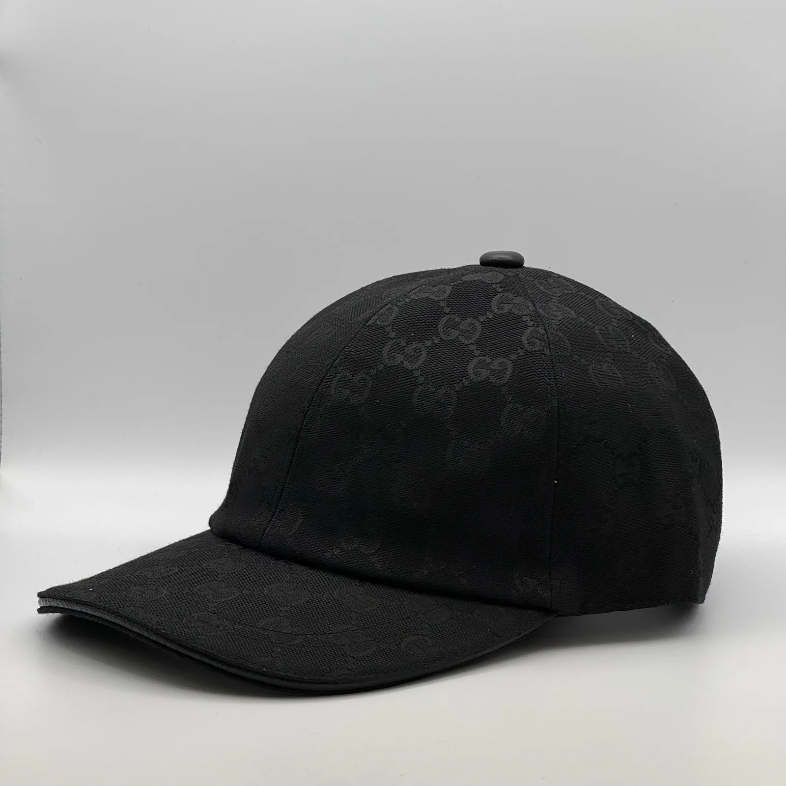 Black GG canvas cap, straight-on front view showing the gold emblem on the crown