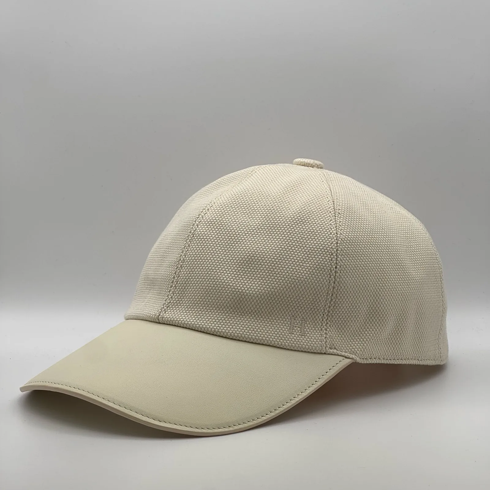 Hermès canvas cap, side profile in cream canvas with a matching cream leather brim.