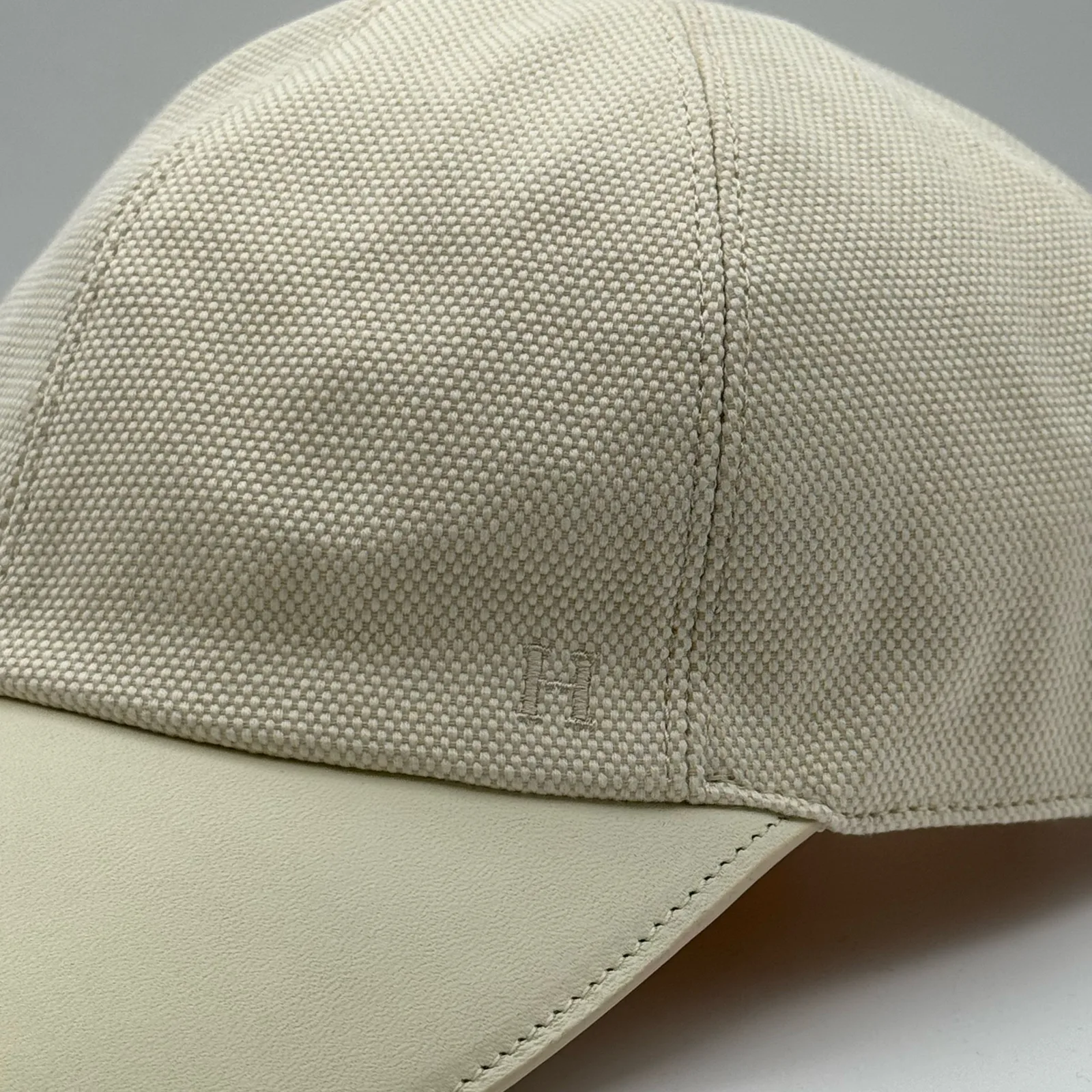 Close-up of the cream leather brim meeting the cream canvas crown, with a small tone-on-tone logo.