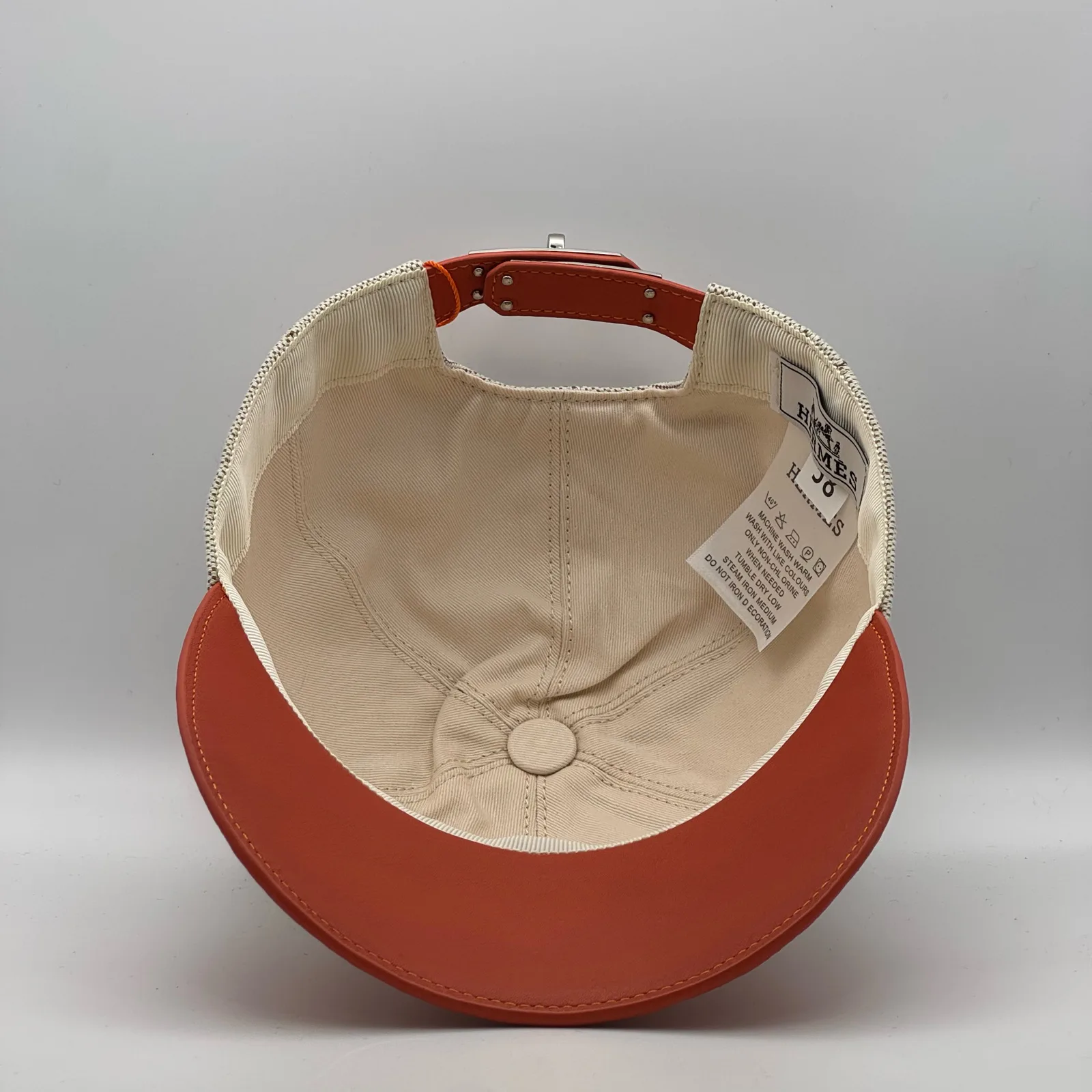Hermès canvas cap, underside view showing the cream interior lining and orange brim.