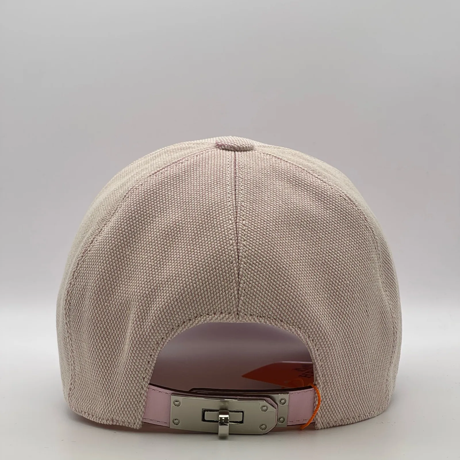Hermès canvas cap, back view showing the pink leather strap and metal buckle closure.