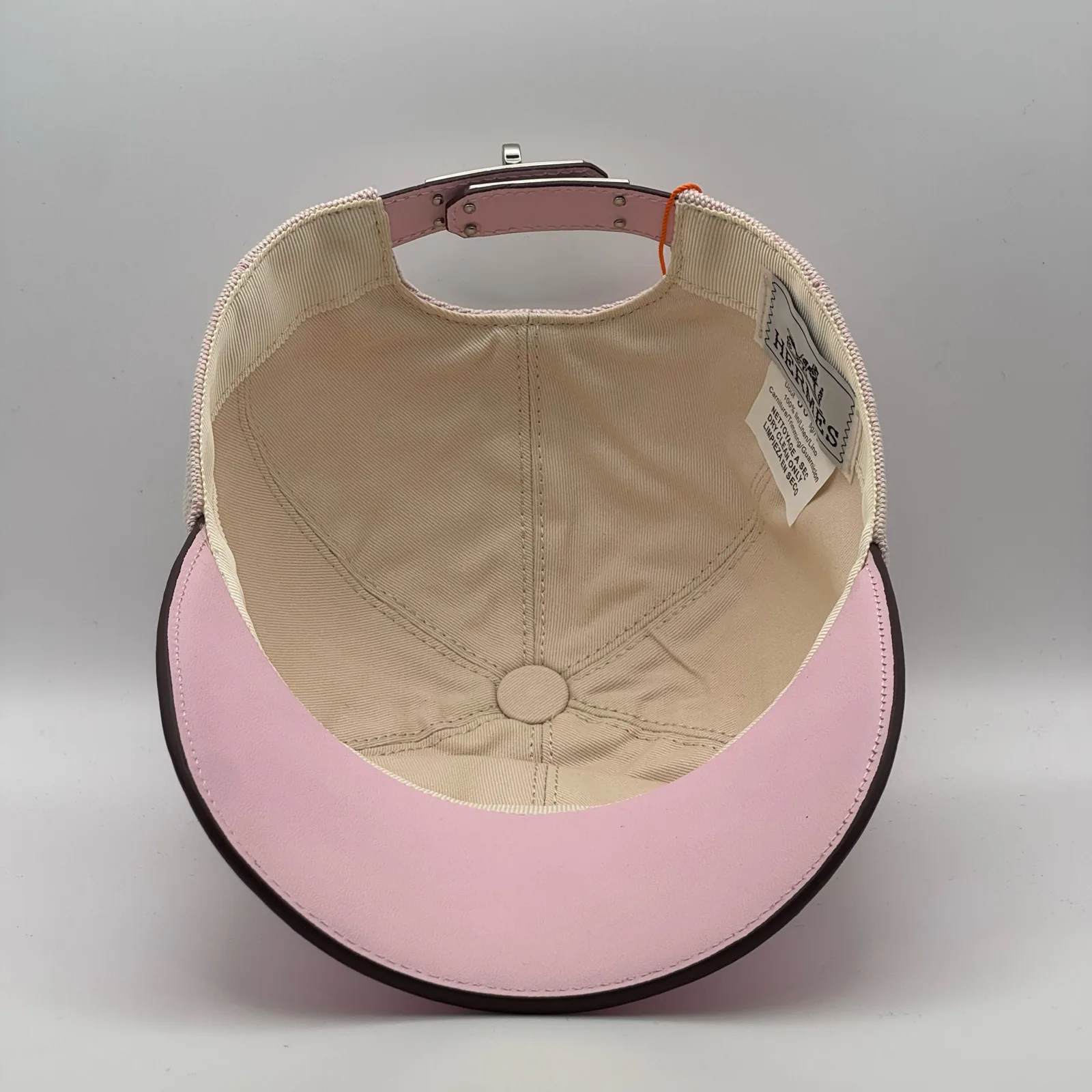 Hermès canvas cap, underside view showing the cream interior lining and pink brim.
