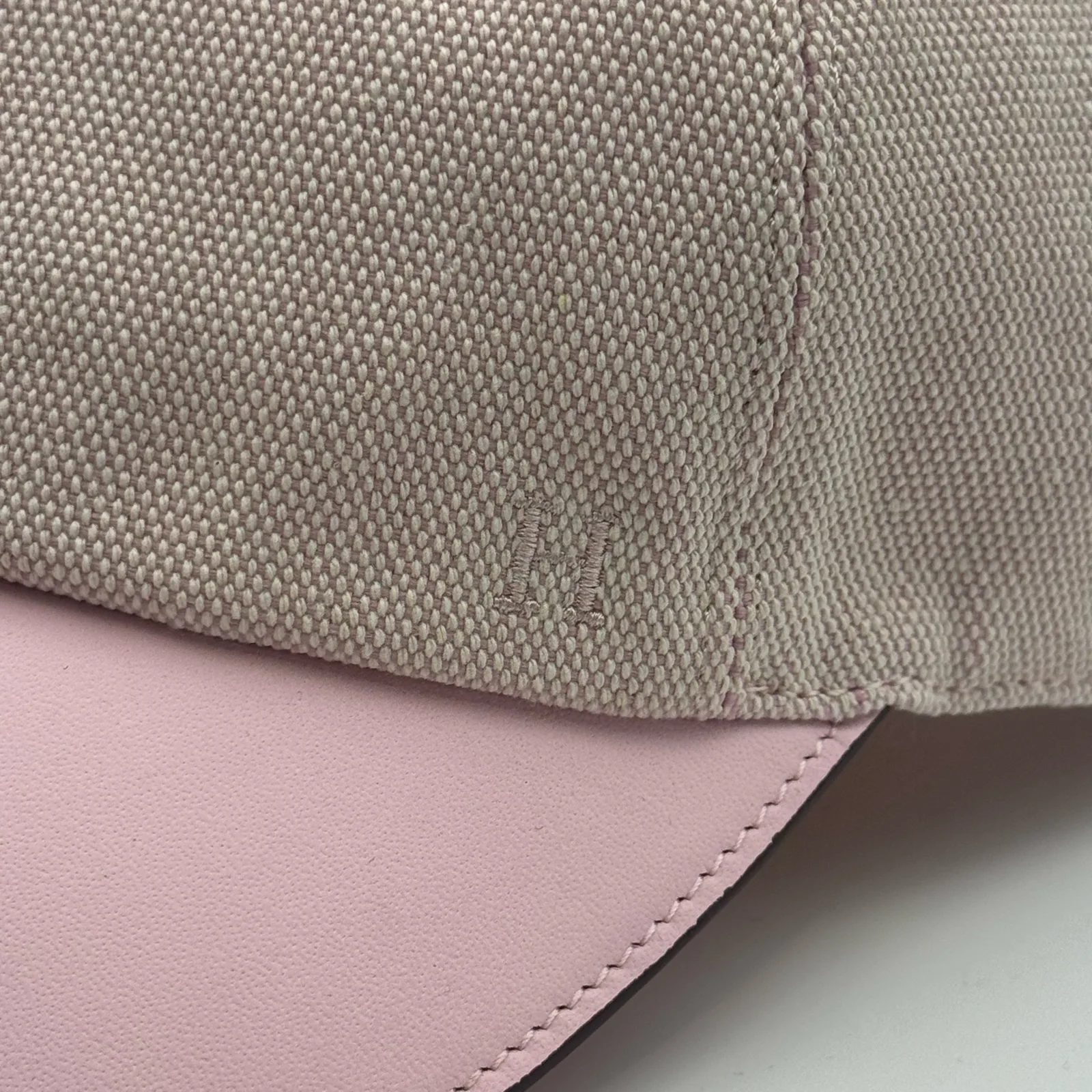 Close-up of the pink leather brim meeting the woven canvas crown, with a small tone-on-tone logo.