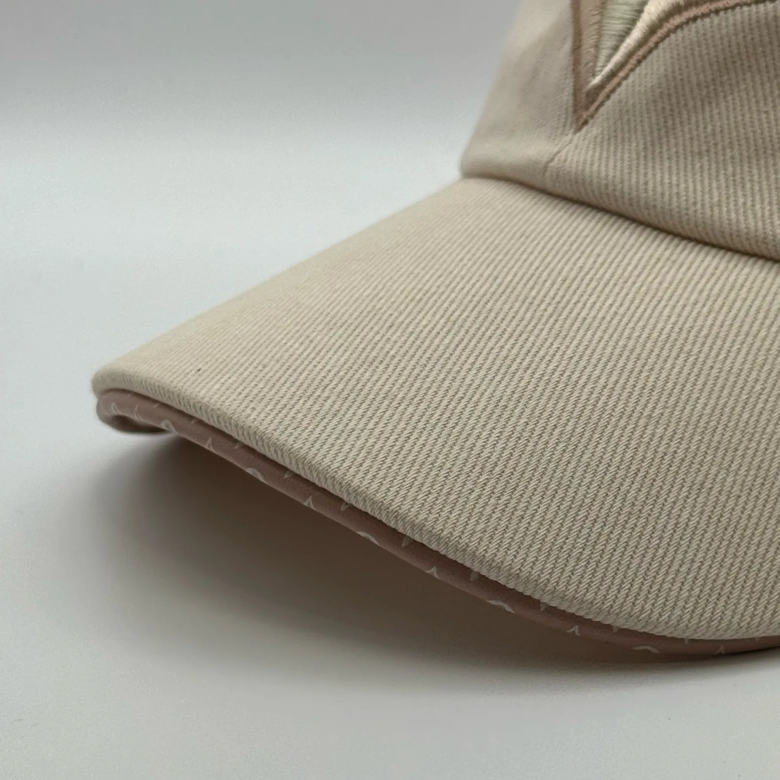 Close-up of the brim edge and tonal stitching on the beige flower cap.